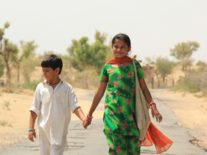 Zwei Kinder laufen auf einer Straße in Indien entlang