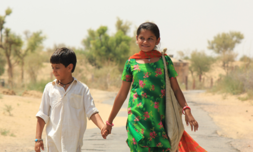 Zwei Kinder laufen auf einer Straße in Indien entlang
